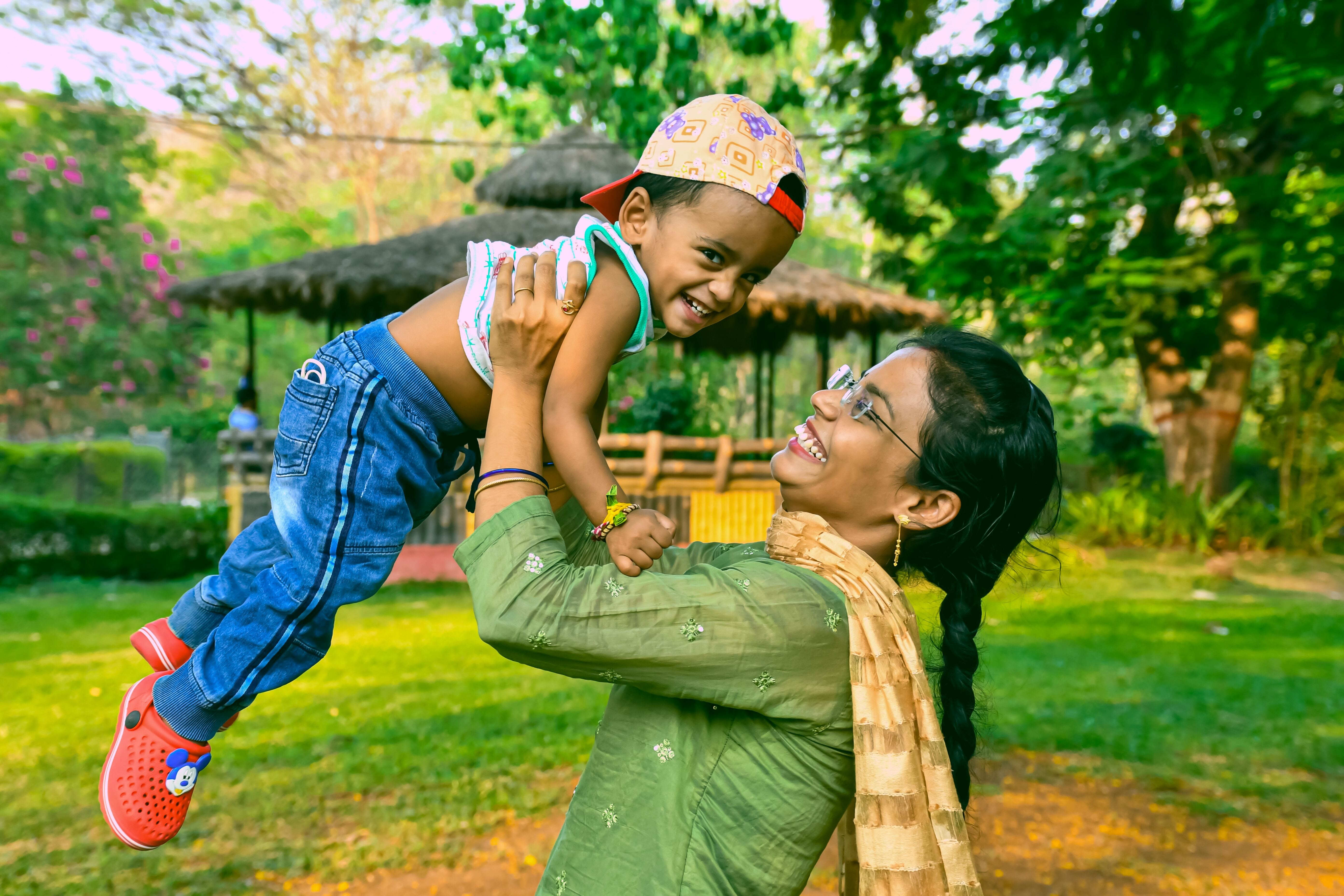 Mother joyfully lifting her young child in a sunlit garden